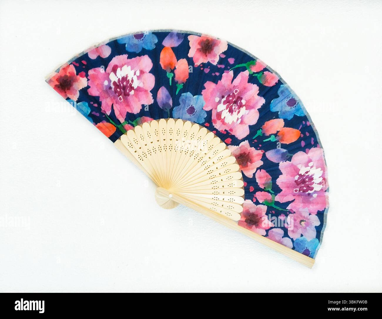 an open hand fan adorned with a delightful floral pattern. Stock Photo