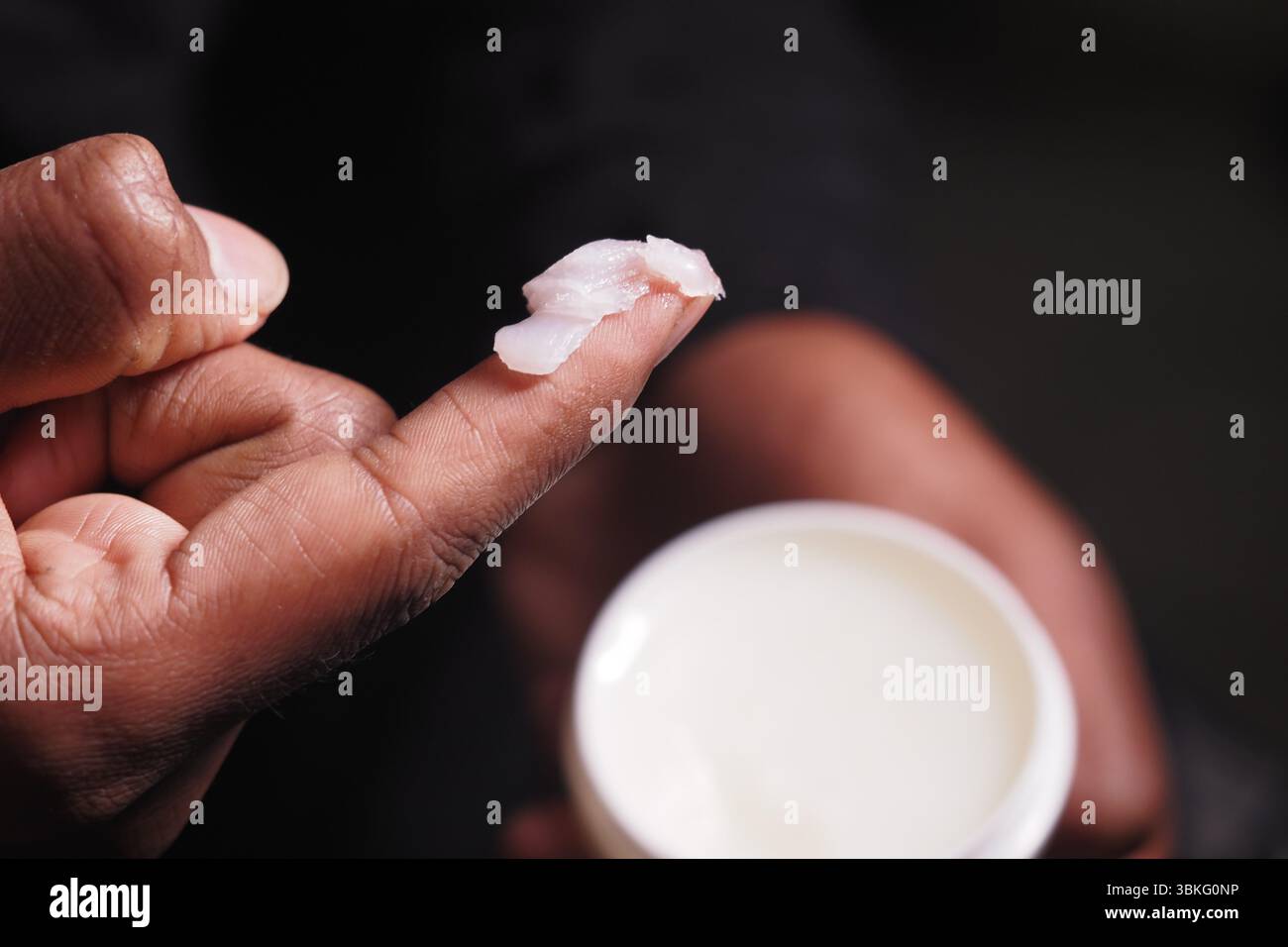 Hand applying moisturizer in a well-lit space Stock Photo