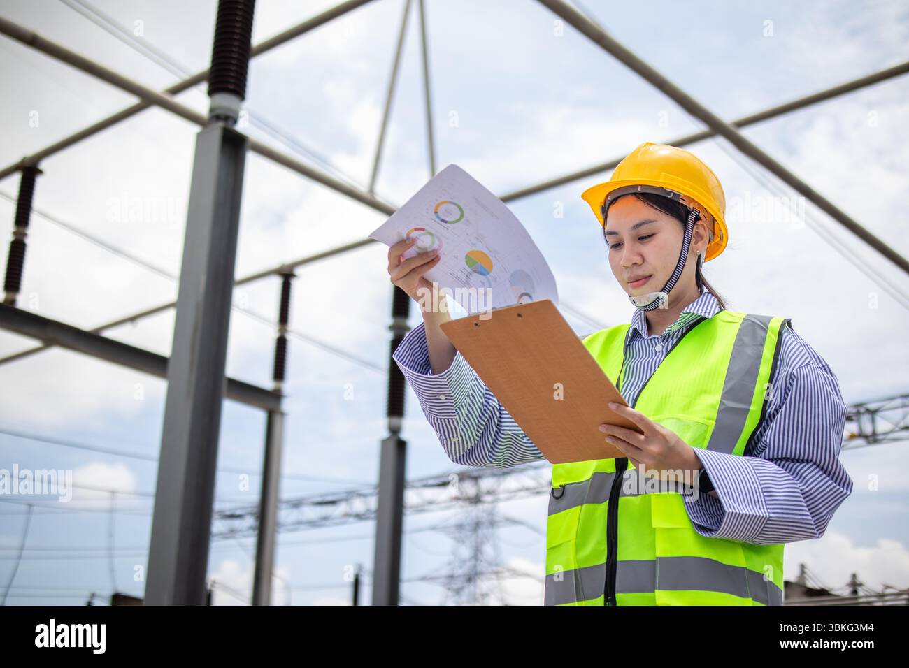 A power substation engineer wearing safety gear reviews work documents