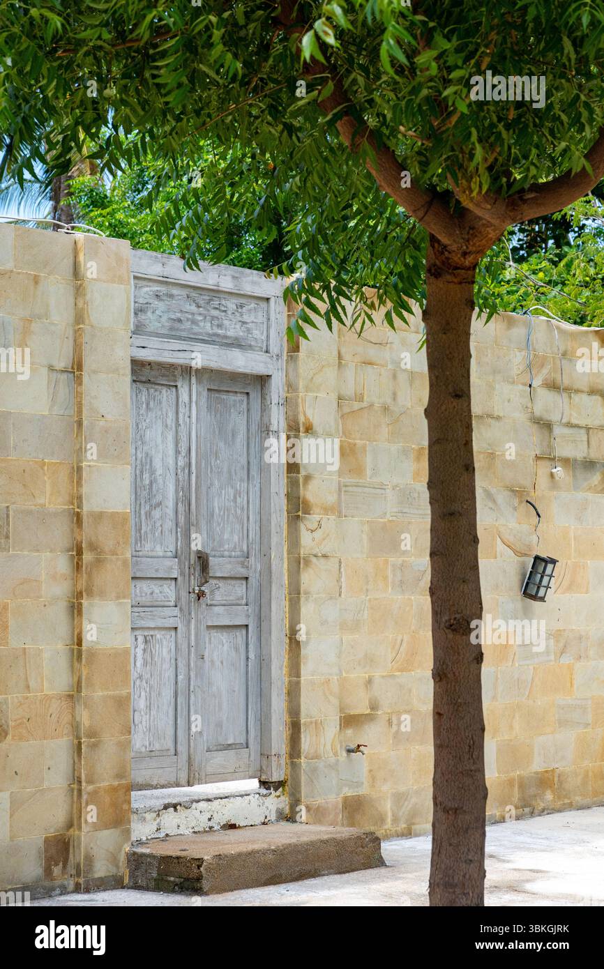 White door with a wooden frame is in front of a brick wall. The door is open and the wall is covered in bricks Stock Photo