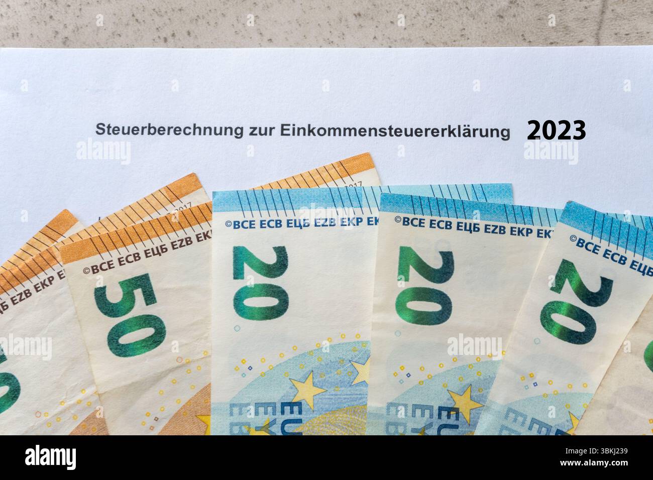 Paper form for tax return in 2023 year. Einkommensteuererklärung and income in euro money bills. Steuer in Germany. Stock Photo