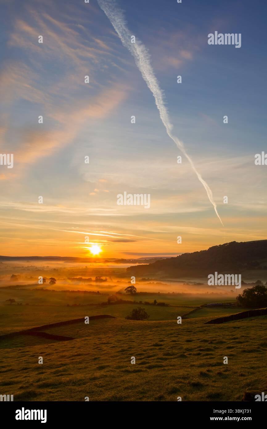 Early autumn sunrise view with the sun rising over low lying mist looking along the Esk valley within the North York Moors national park - Stock Image