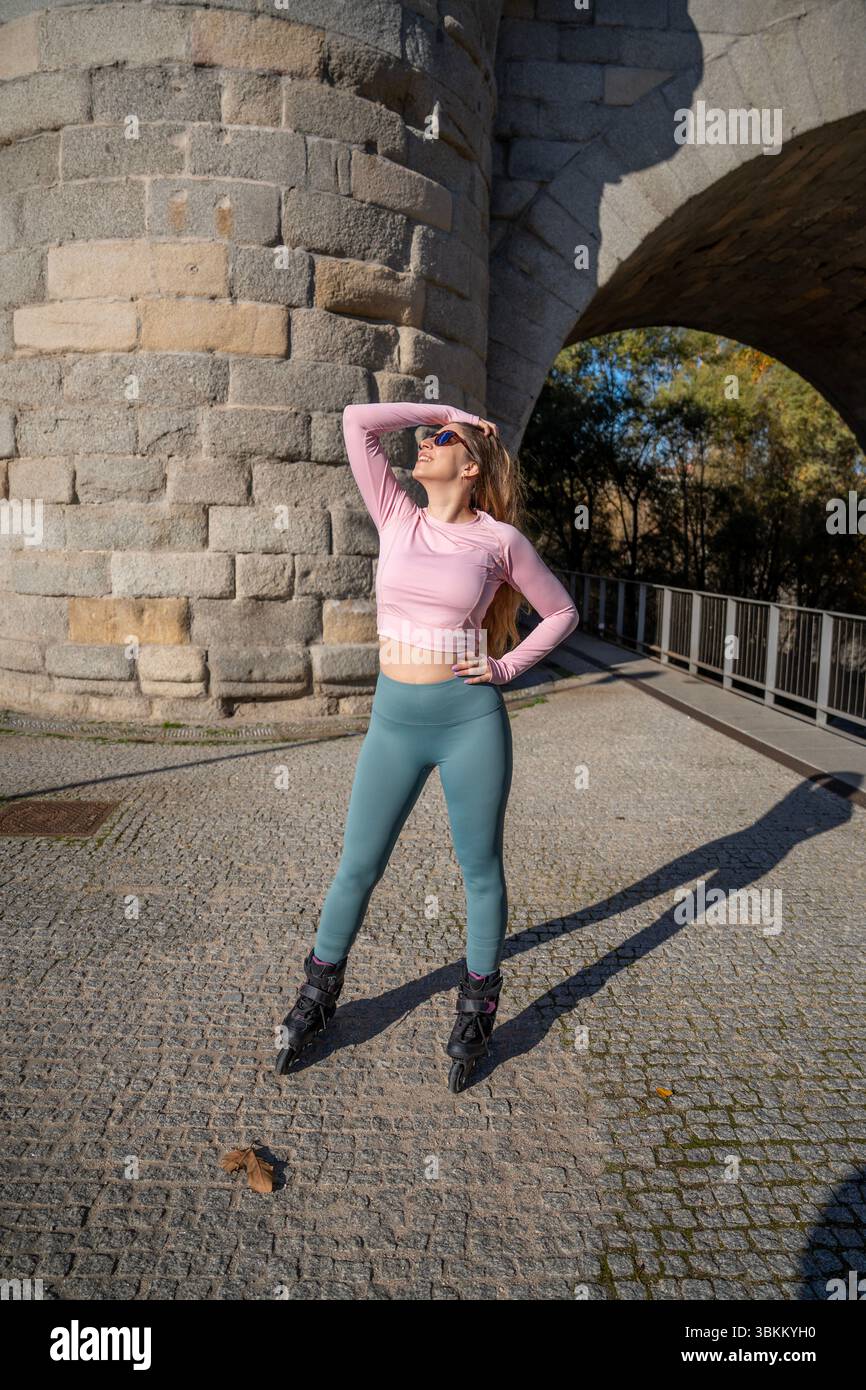 Young sporty woman posing with inline skates under a bridge during a sunny day Stock Photo