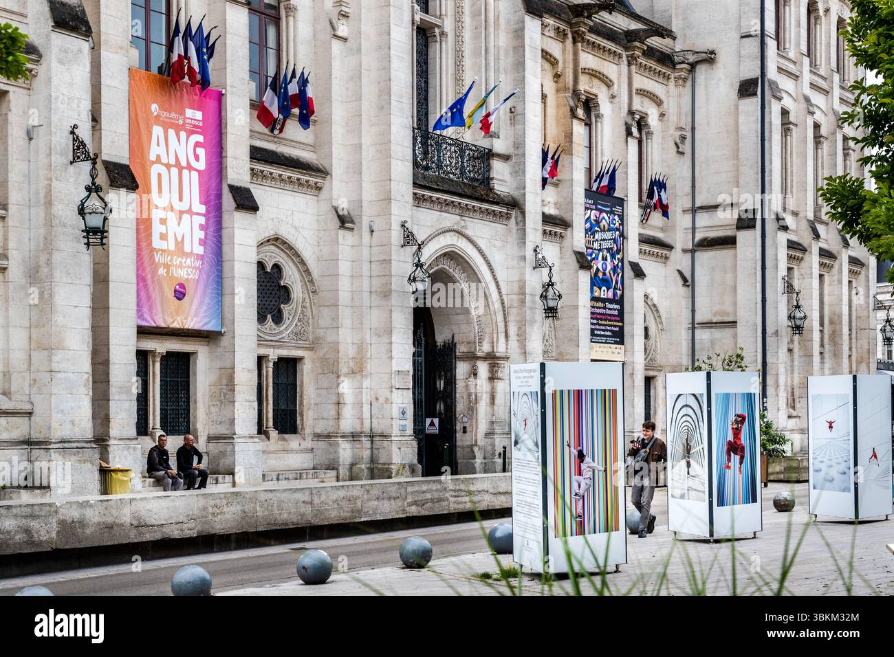 Angoulême town hall with French flags and banners advertising events, including the ‘Festival Musiques Métisses’ and the ‘Festival Limo Photogaphique’. The city is recognized as a UNESCO Creative City in the category of literature since 2019. Place de l'Hôtel de ville, Angoulême, Nouvelle-Aquitaine, France Stock Photo