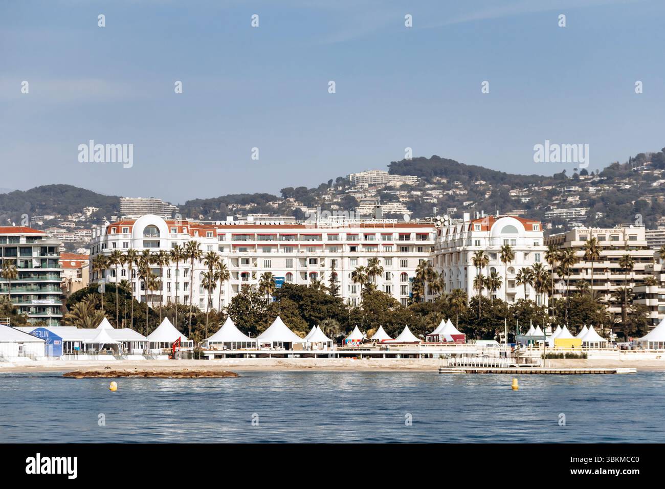 Cannes, France - March 8, 2025: Palais des Festivals and luxury hotels on the Croisette waterfront with city hills in the background. Stock Photo