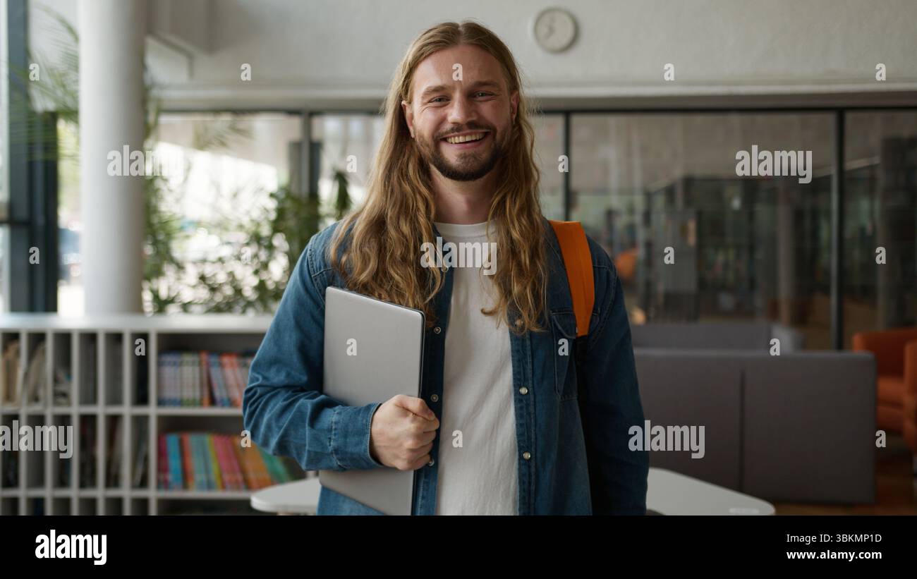 Caucasian student guy man male posing in university college academy hall corridor holding laptop smiling happy looking at camera studying learning Stock Photo