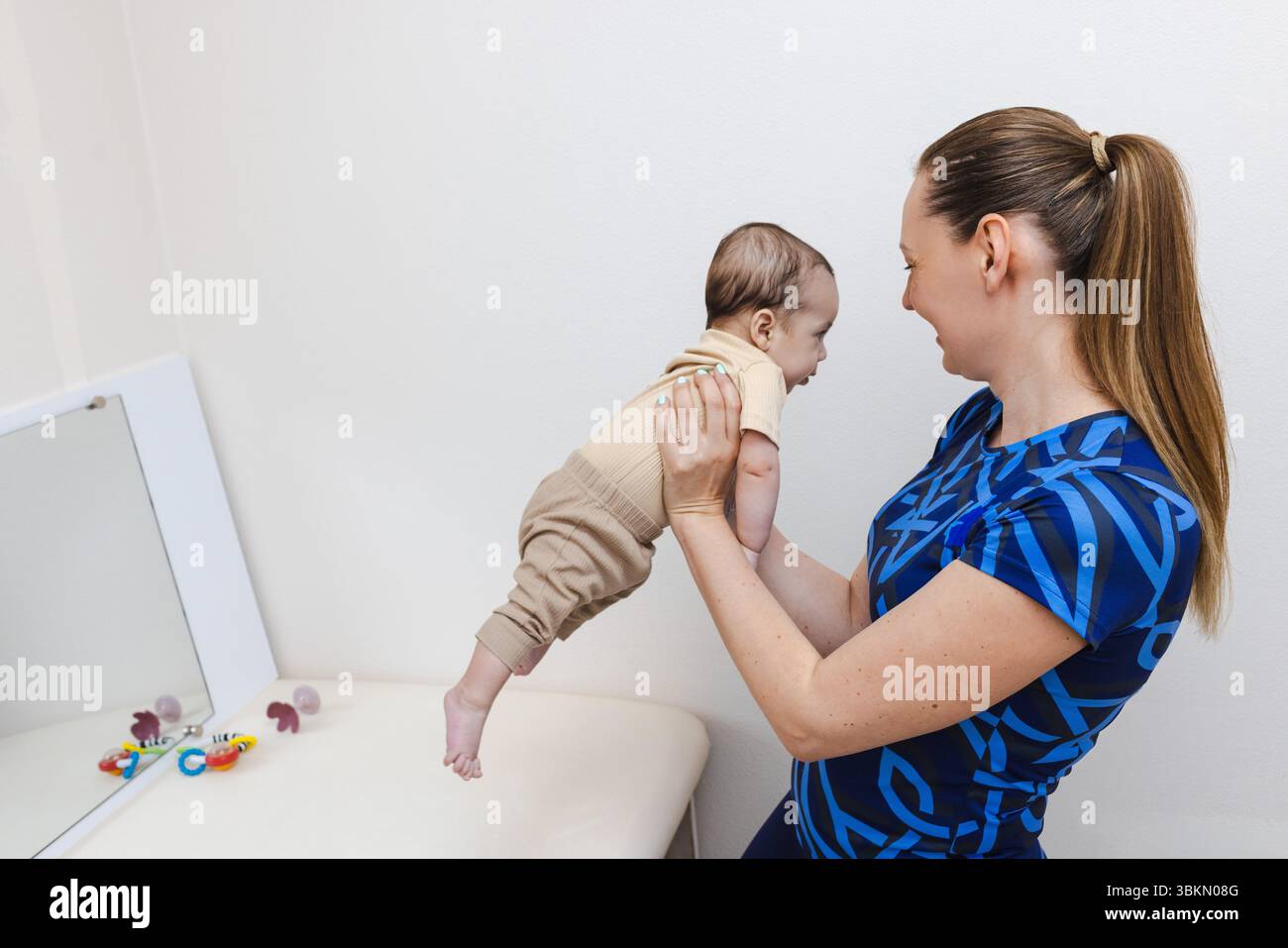 Pediatric physical rehabilitation session led by a therapist to enhance a toddler motor abilities and overall health Stock Photo