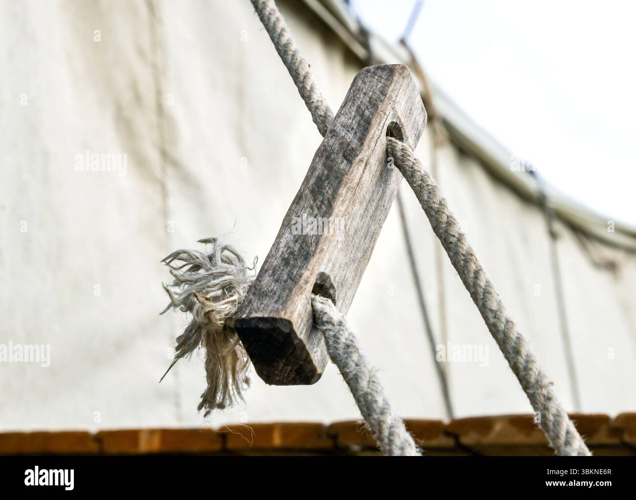 Using a wooden block with holes as a tent guy line anchor Stock Photo