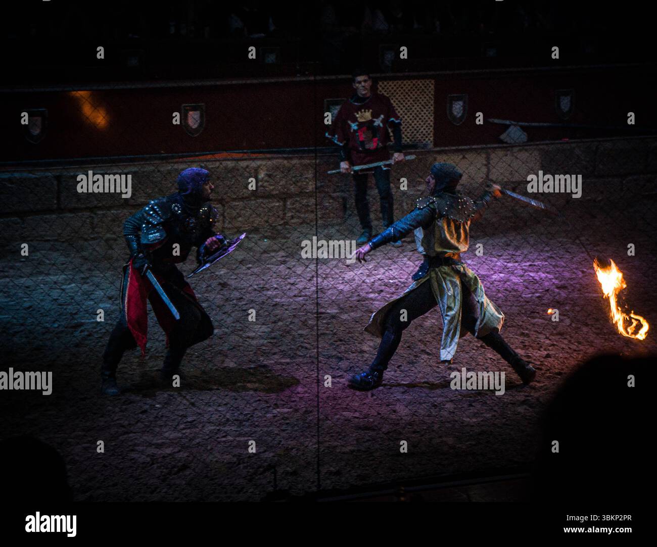 Two medieval knights clash in a dark arena, their swords flashing in ...