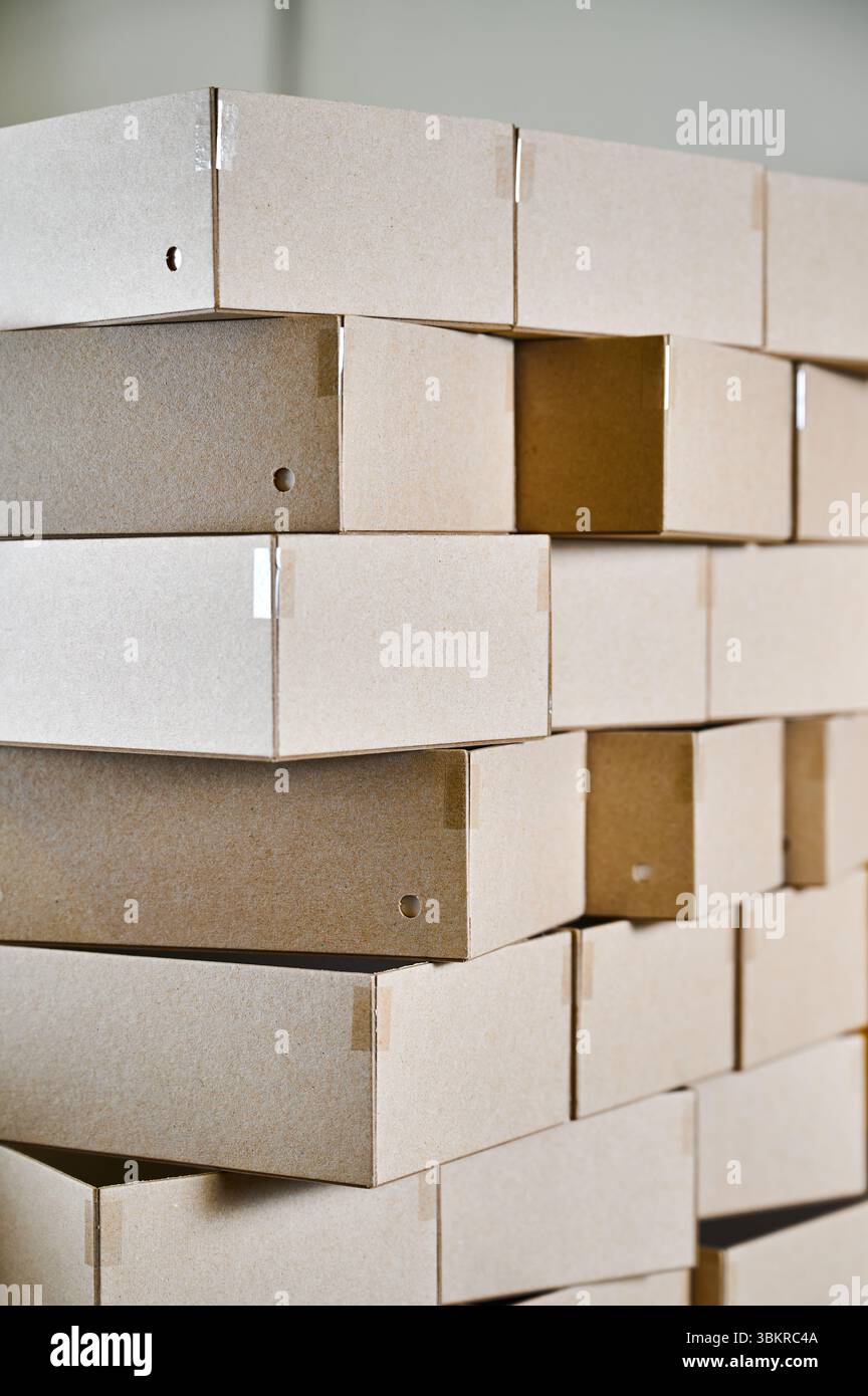 Cardboard box blanks stacked for efficient packaging production in a busy cardboard manufacturing facility Stock Photo