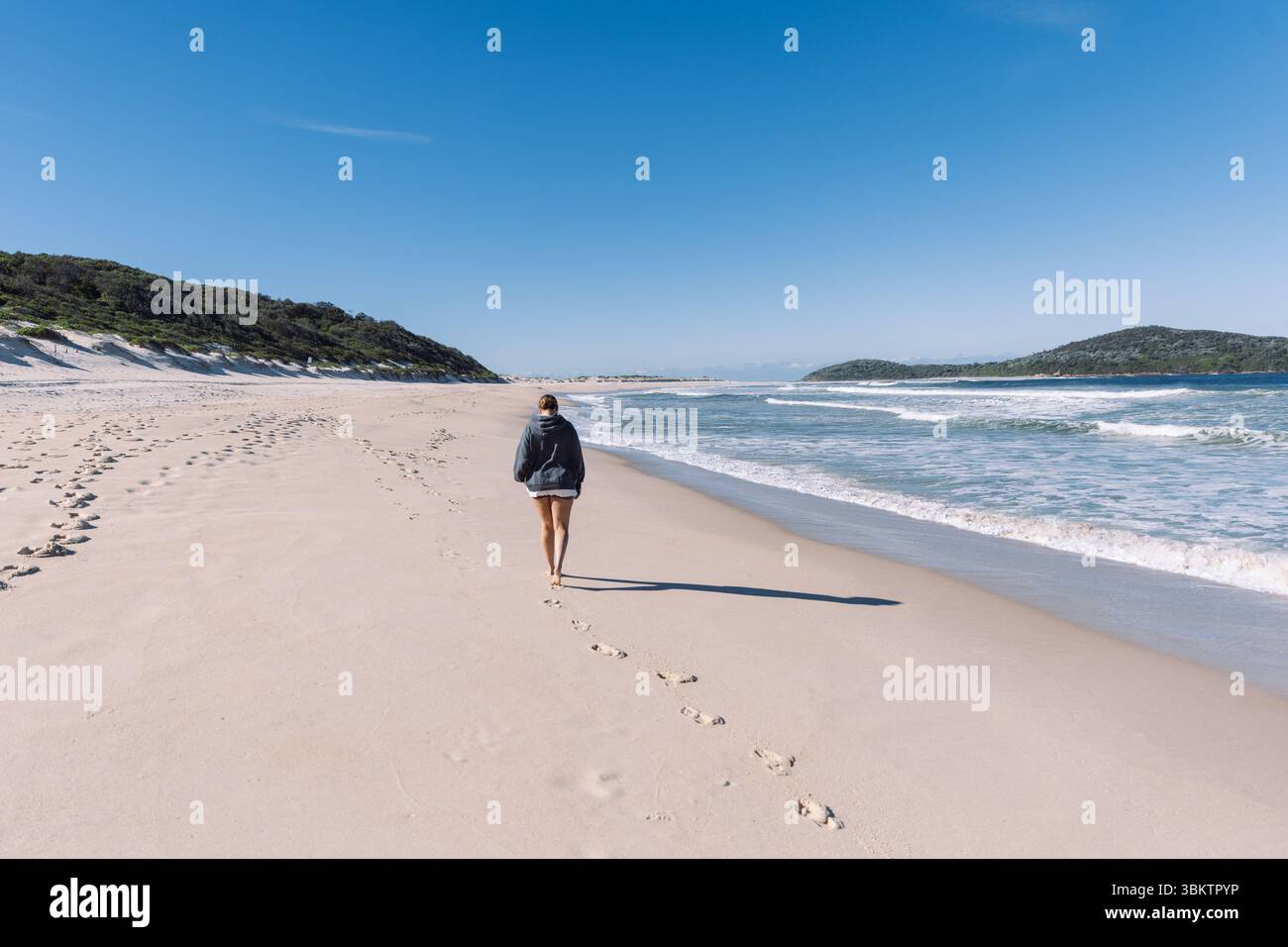 Tourist walking on the beach leaving footprints in the sand Stock Photo ...