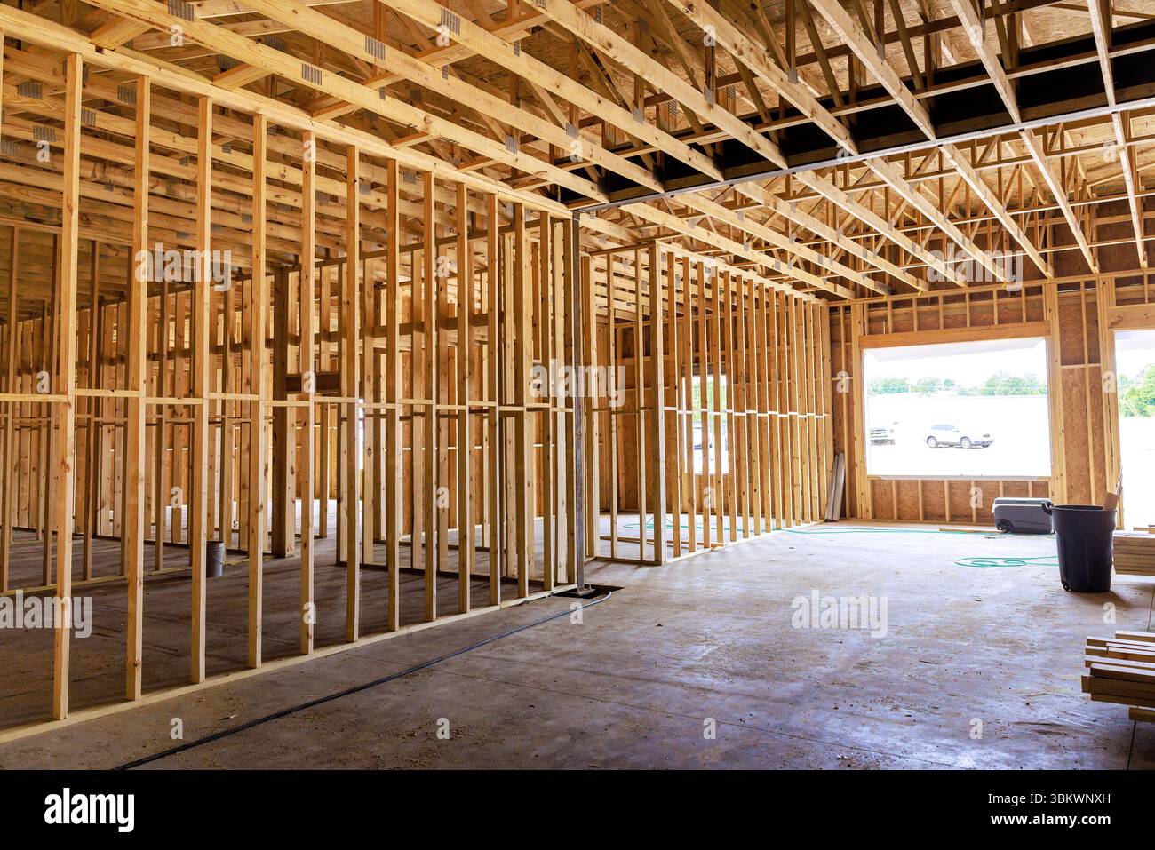 Wooden framing structure is taking shape inside building, revealing an open layout under natural light at site. Stock Photo