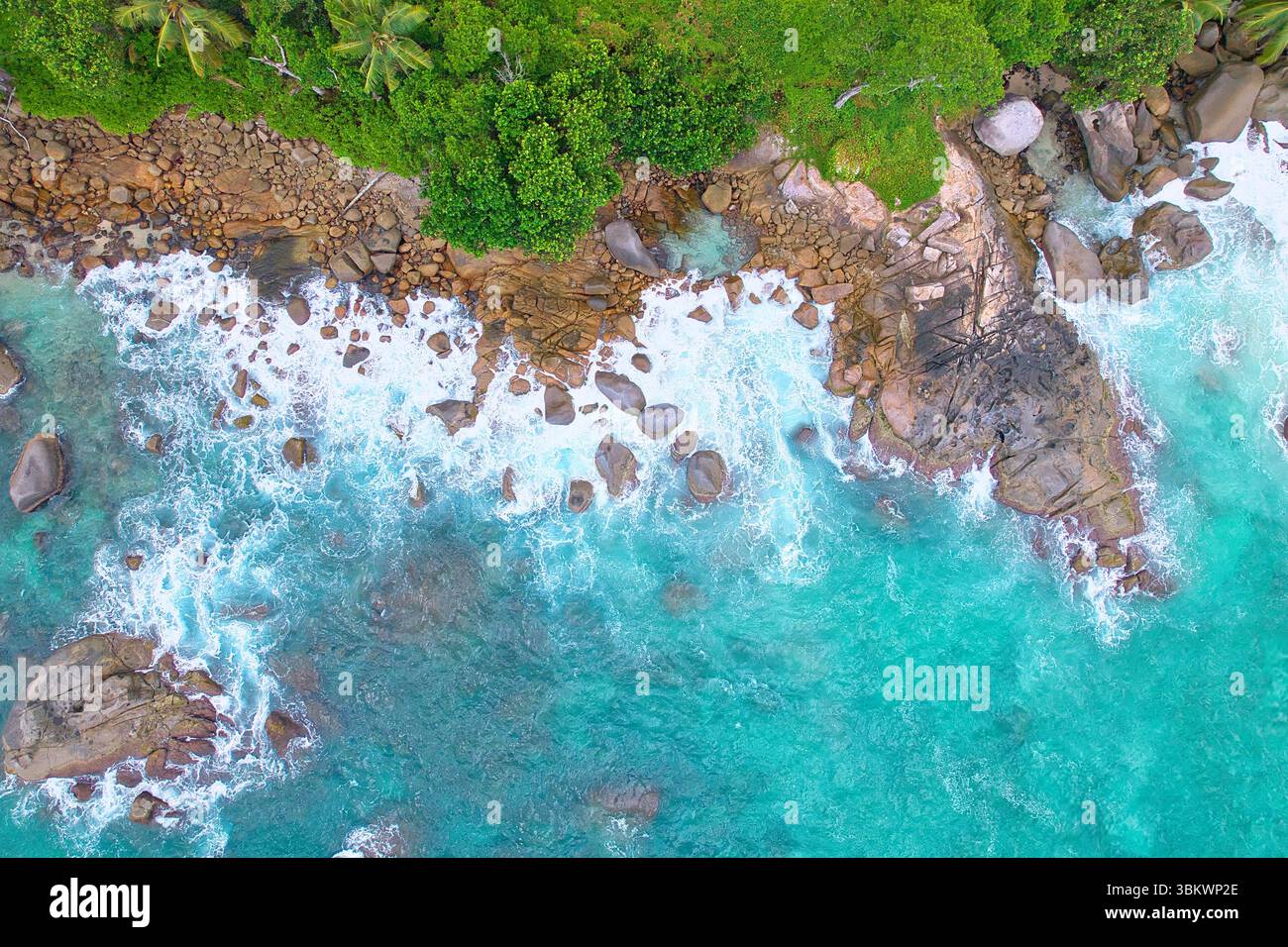 Bird eye drone shot of granite stones, wavy ocean, with small rock pool, Mahe Seychelles Stock Photo