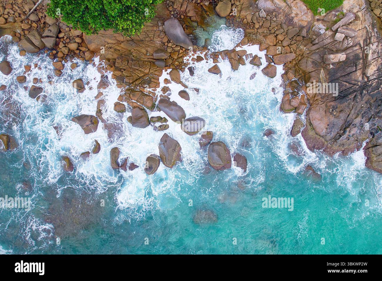 Bird eye drone shot of granite stones, wavy ocean, with small rock pool, Mahe Seychelles Stock Photo