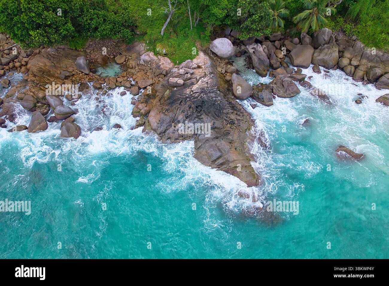 Bird eye drone shot of granite stones, wavy ocean, with small rock pool, Mahe Seychelles Stock Photo