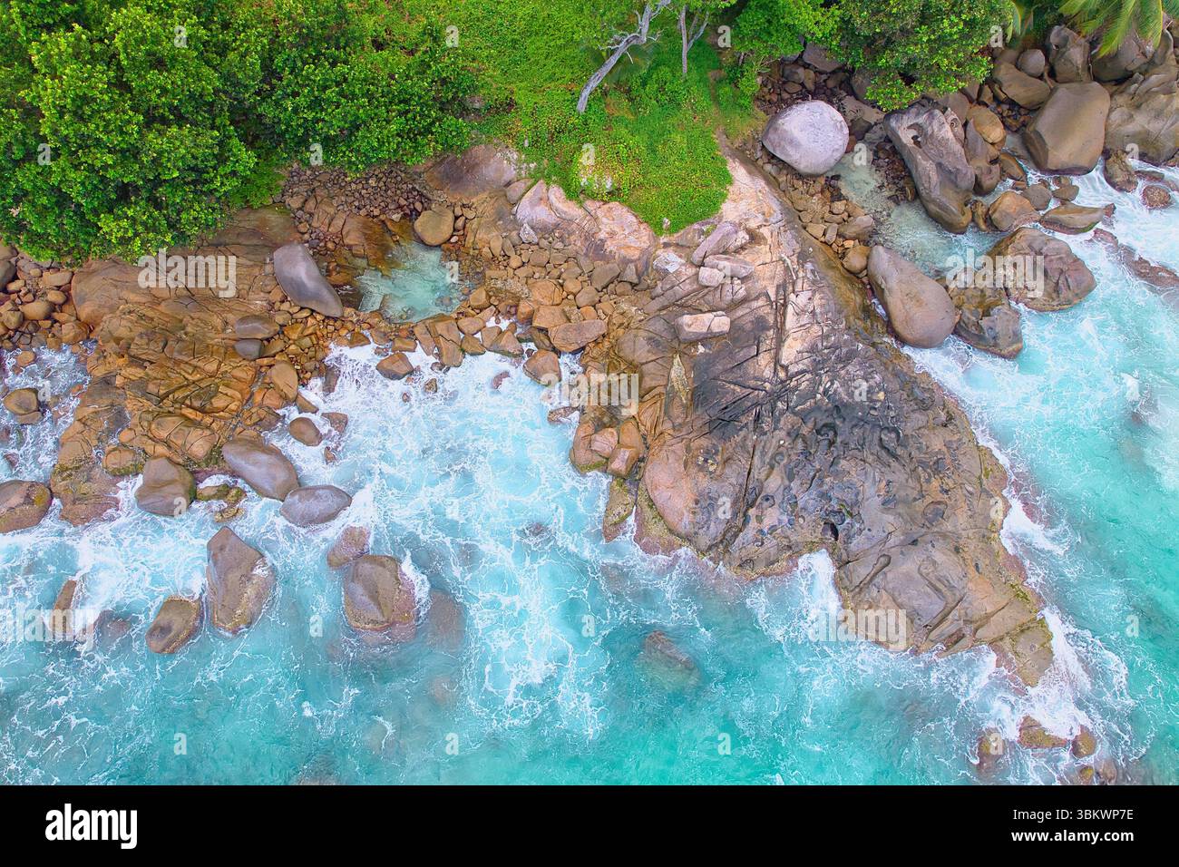 Bird eye drone shot of granite stones, wavy ocean, with small rock pool, Mahe Seychelles Stock Photo
