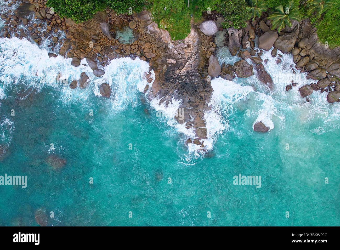 Bird eye drone shot of granite stones, wavy ocean, with small rock pool, Mahe Seychelles Stock Photo
