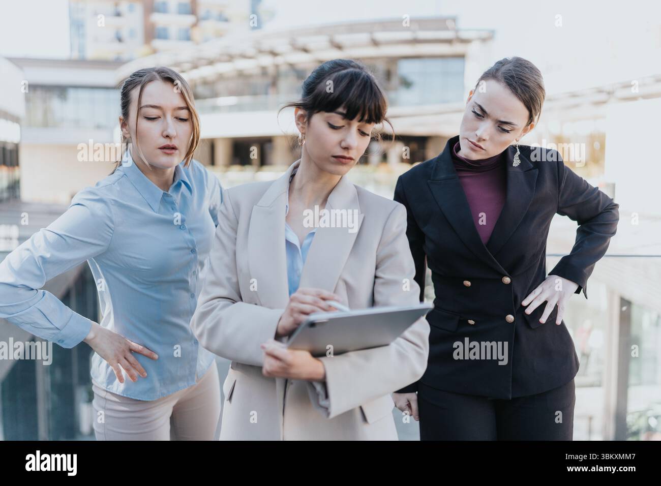 Three female professionals collaborating on a project using a tablet outdoors Stock Photo