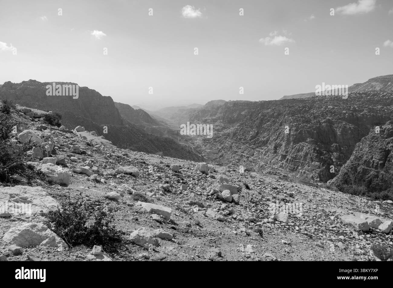 A rocky, barren landscape with a mountain in the background. The sky is cloudy and the sun is not visible Stock Photo