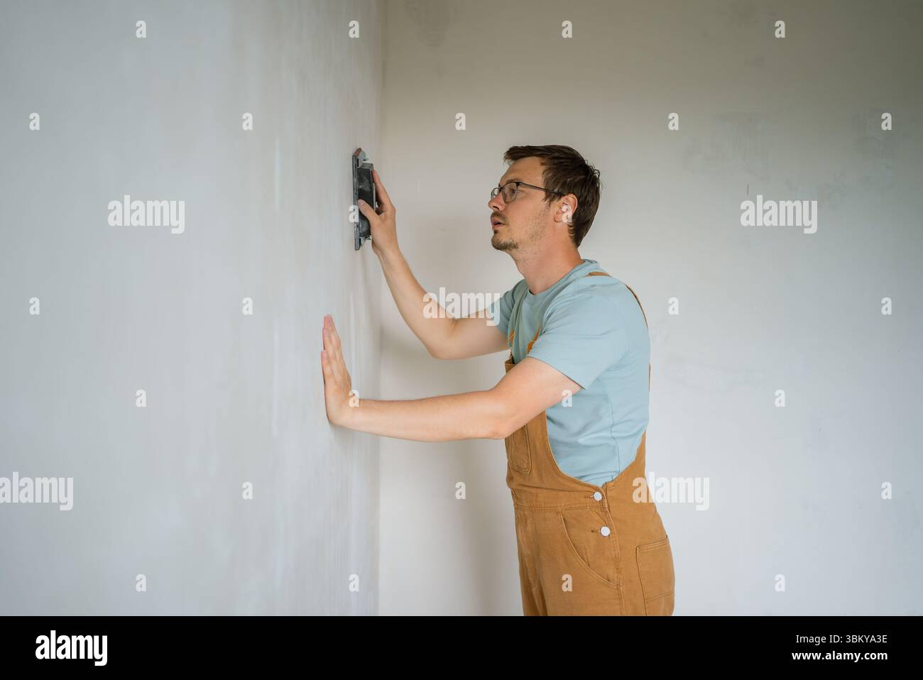 Image showcasing Skilled worker smoothing concrete wall surface, demonstrating precision ...