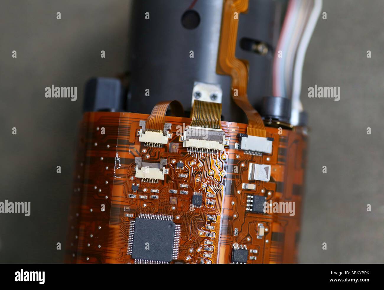 Macro shot of DSLR lens circuit board with flex cables and microchips, revealing detailed internal camera electronics. Stock Photo
