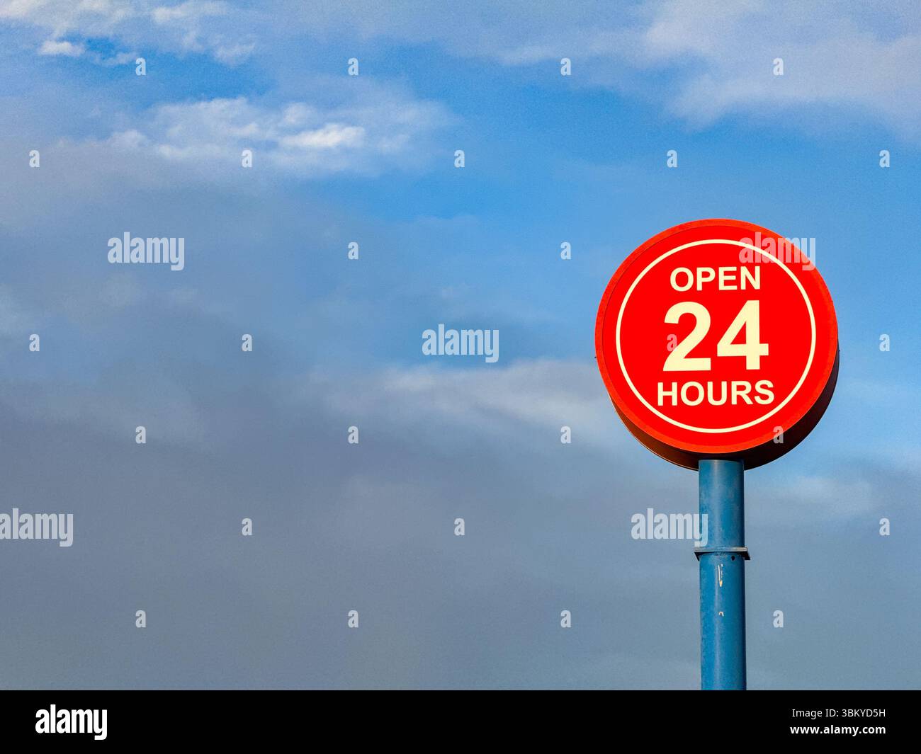 Open 24 hours sign isolated against a blue sky. No people. Copy space. - Smartphone Captured Stock Image