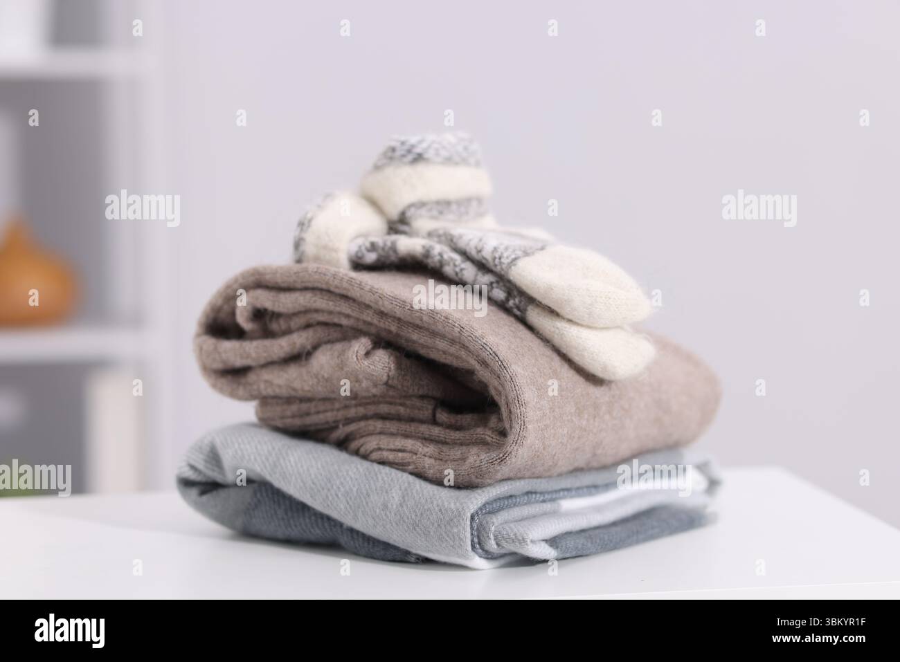 Stack of wool clothes on white table indoors Stock Photo
