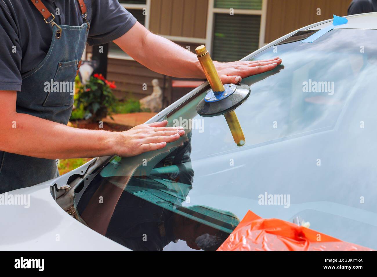 Technician uses suction cup tool to secure new windshield in car at ...