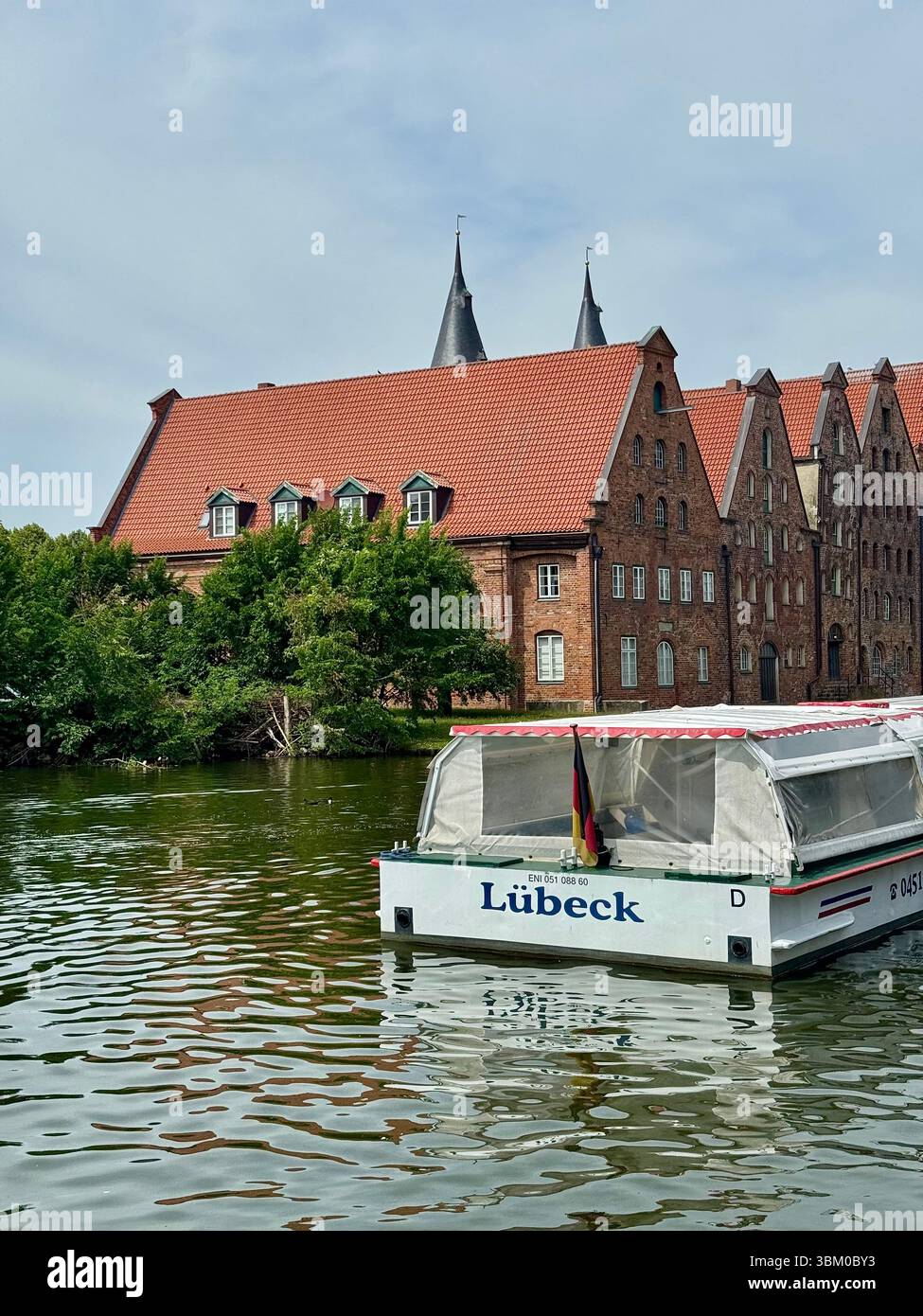 Tourist boat on the Trave River with historic brick buildings in Lübeck, Germany, a UNESCO World Heritage Site - Smartphone Captured Stock Image