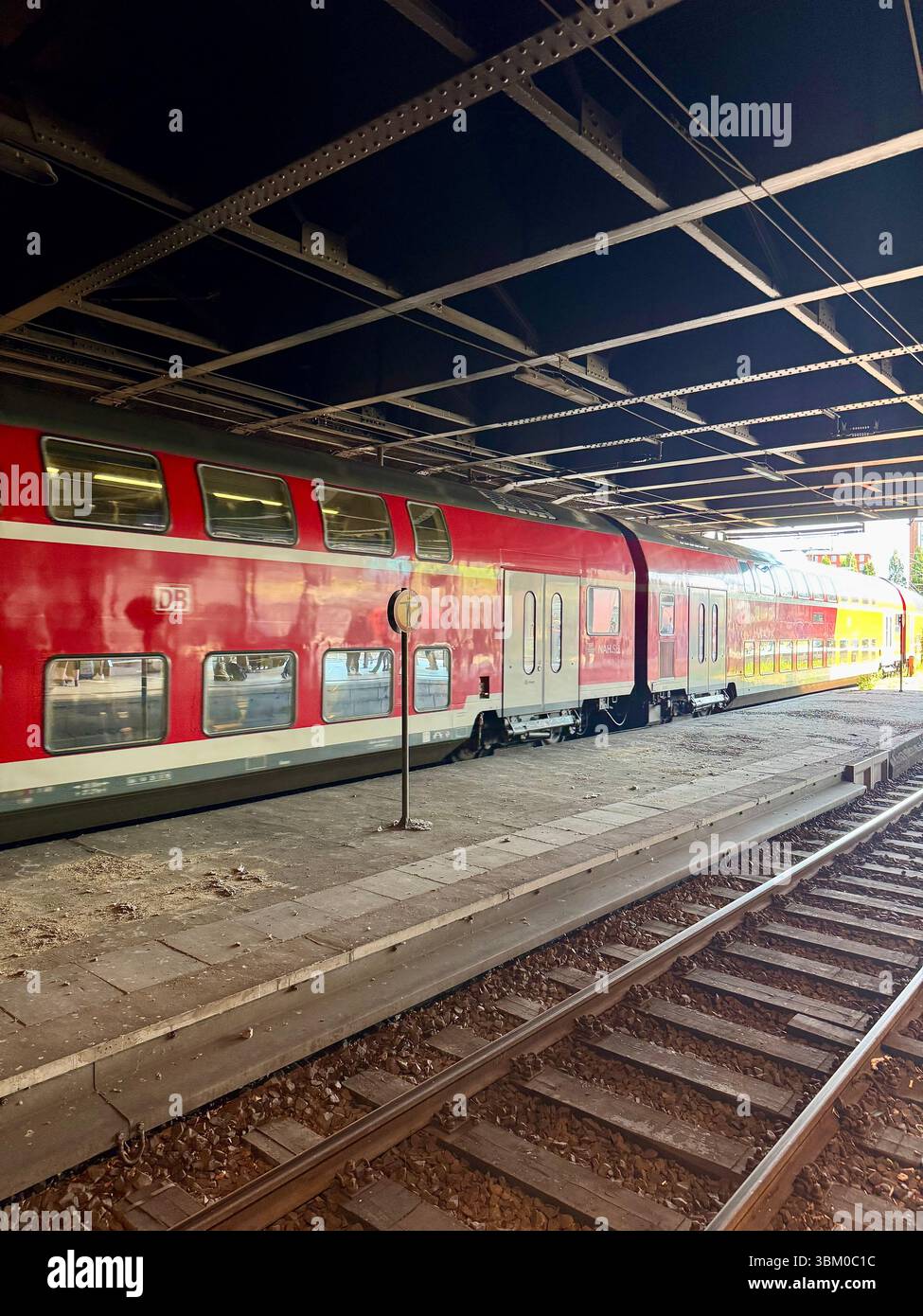 Red double-decker regional train at a platform under a railway bridge in central station, Hamburg, Germany. - Smartphone Captured Stock Image