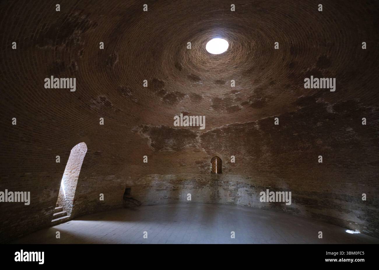 Interior view with light shining through the central oculus hole in the top of the dome. At the dome shaped Sardoba building in Qarshi, Uzbekistan. Stock Photo