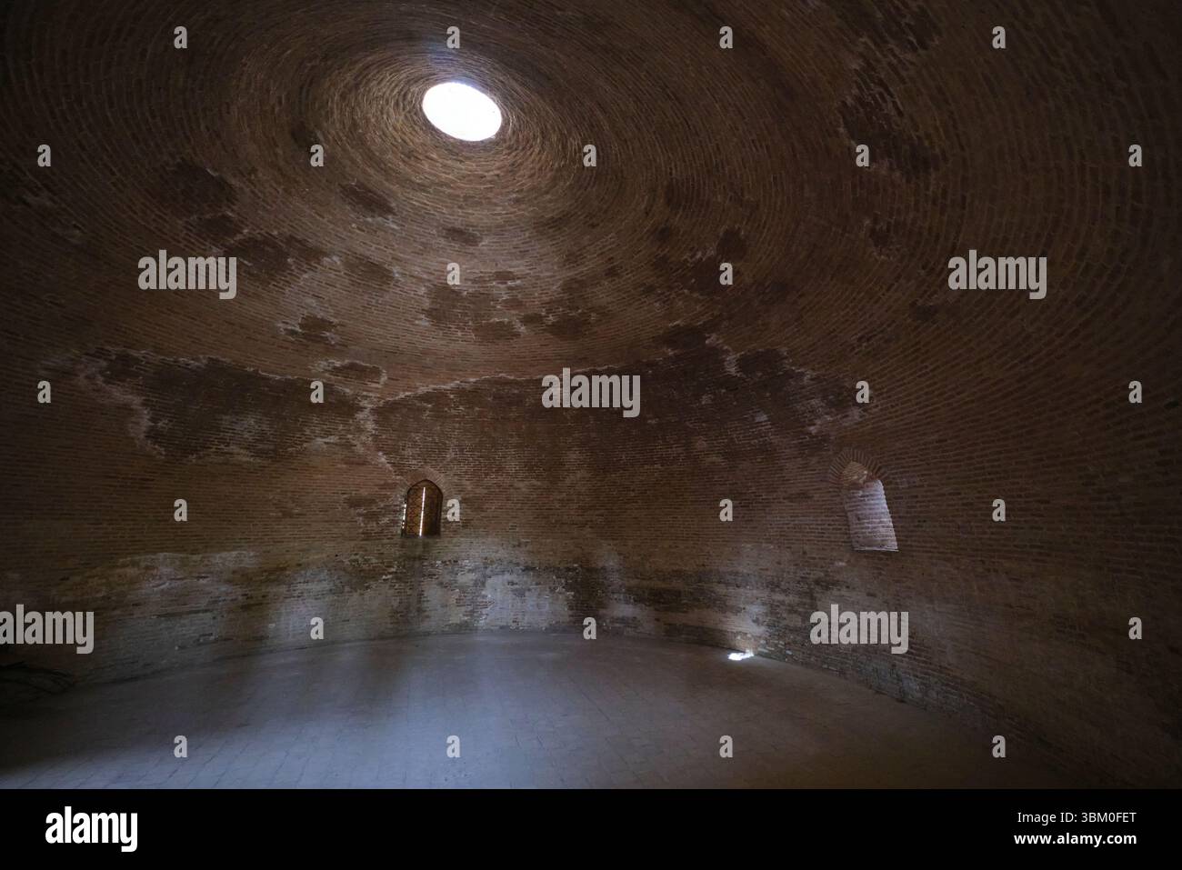 Interior view with light shining through the central oculus hole in the top of the dome. At the dome shaped Sardoba building in Qarshi, Uzbekistan. Stock Photo