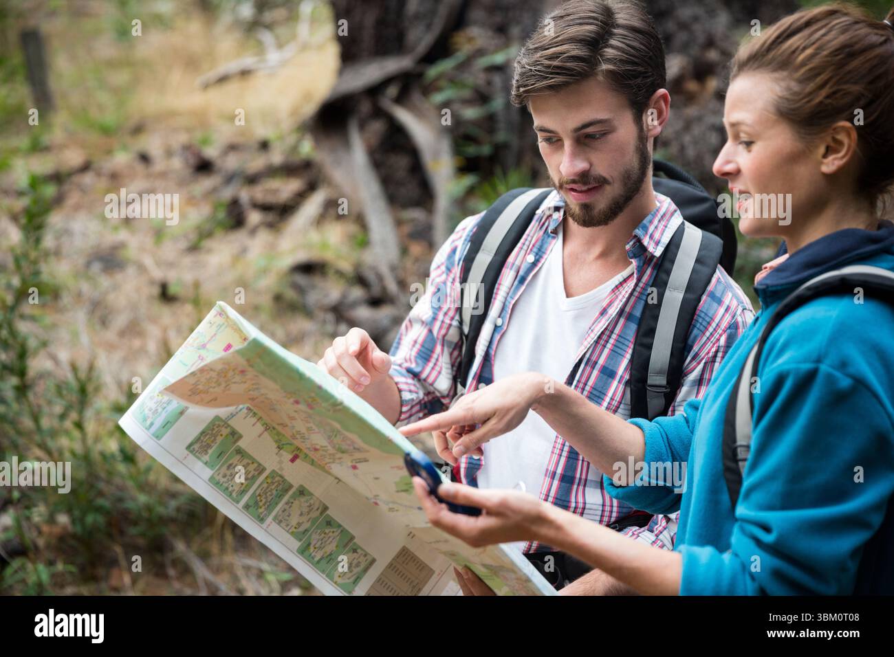 Couple discussing over map in forest Stock Photo