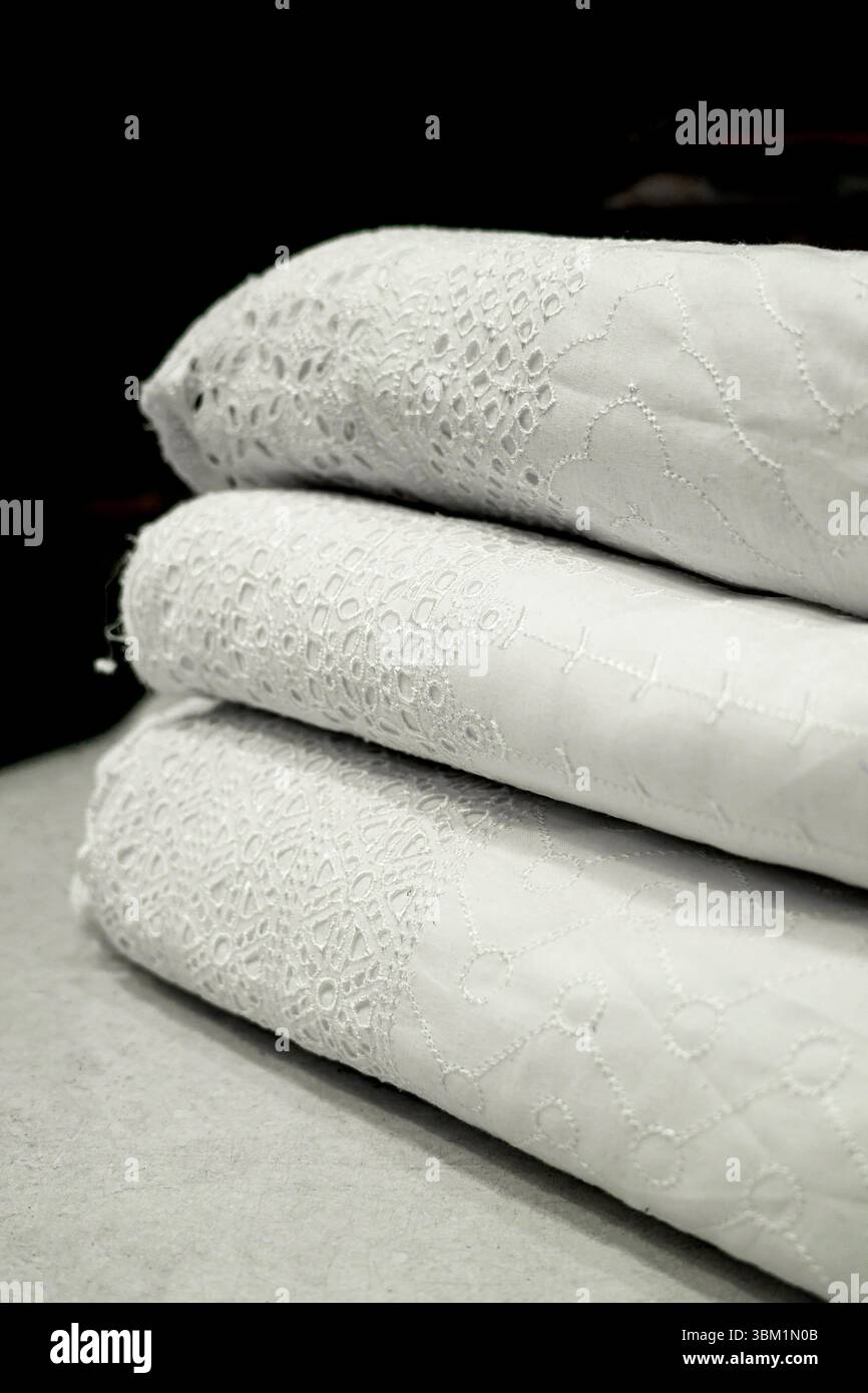 Thread Eyelet Texture A stack of luxurious white eyelet fabric, showcasing intricate lace ...