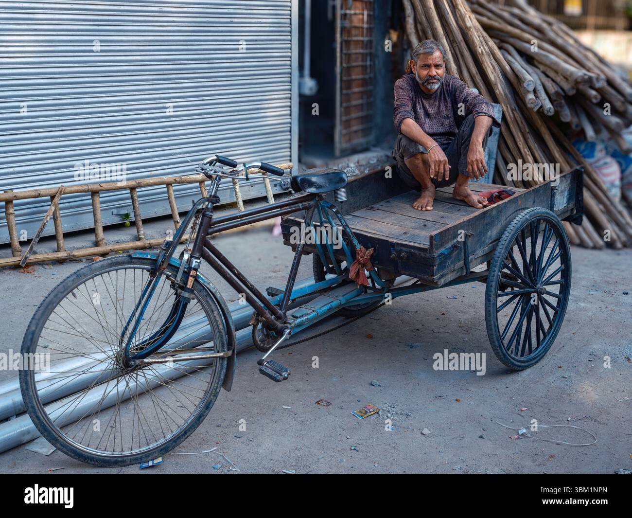 Varanasi Rickshaws India, Varanasi, 16 Mar 2025. Rickshaw puller rests atop his three ...