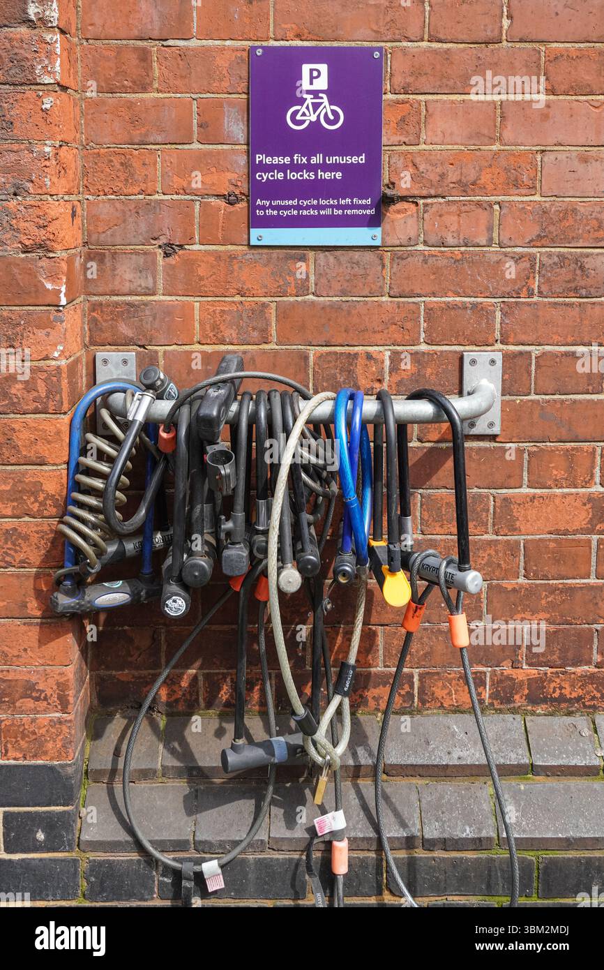 Bicycle locks, cycle locks  hanging fixed to the wall next to bicycle rack in London England United Kingdom UK Stock Photo