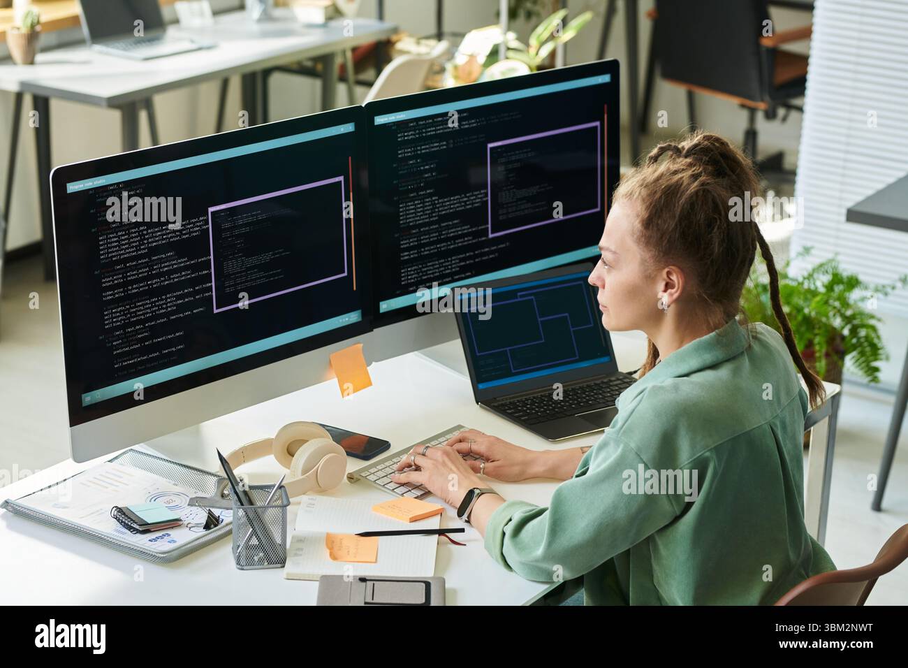 Young Caucasian Woman Developing Neural Network Code on Multiple Monitors Stock Photo