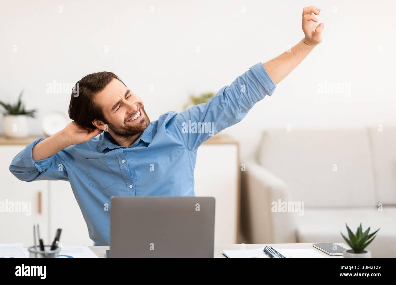 Man Massaging Aching Neck After Work At Computer In Office Stock Photo