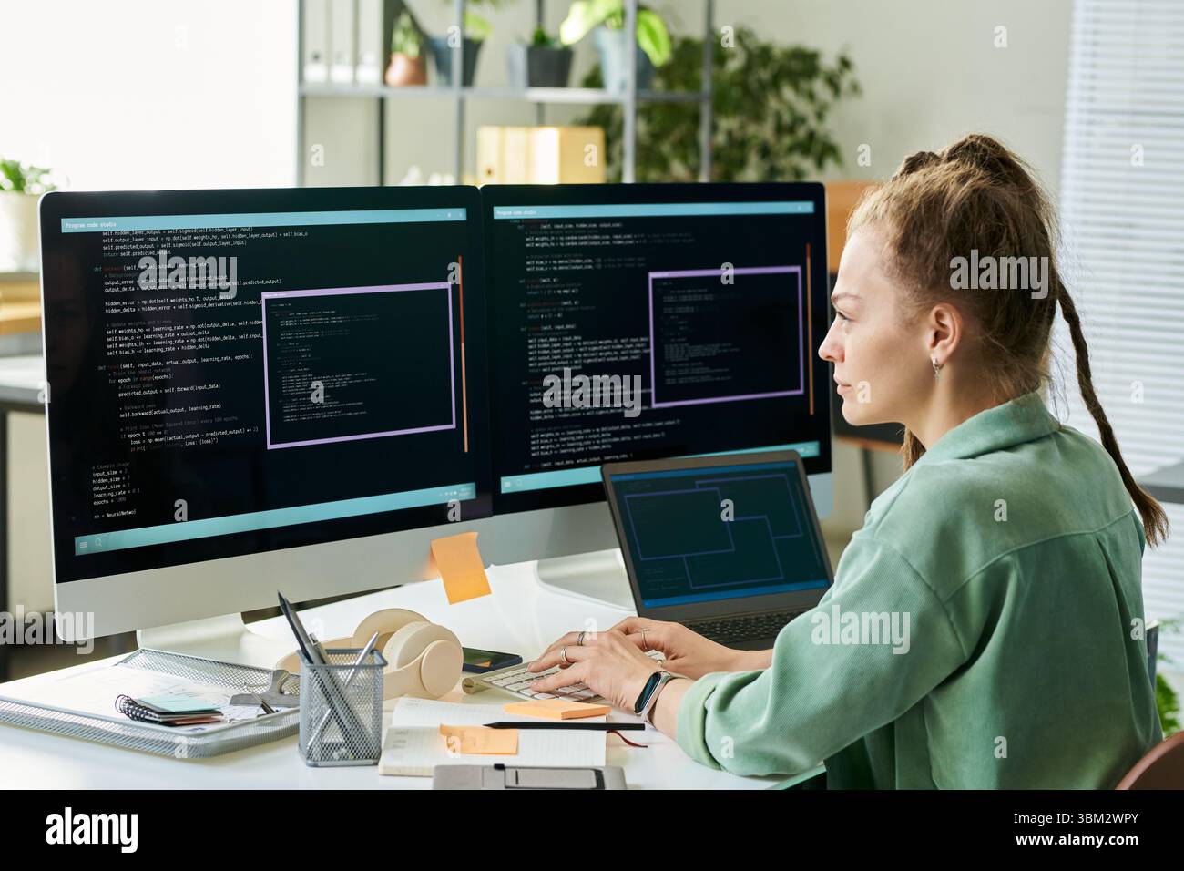 Young Caucasian Woman Developing Neural Network Code on Dual Monitors Stock Photo