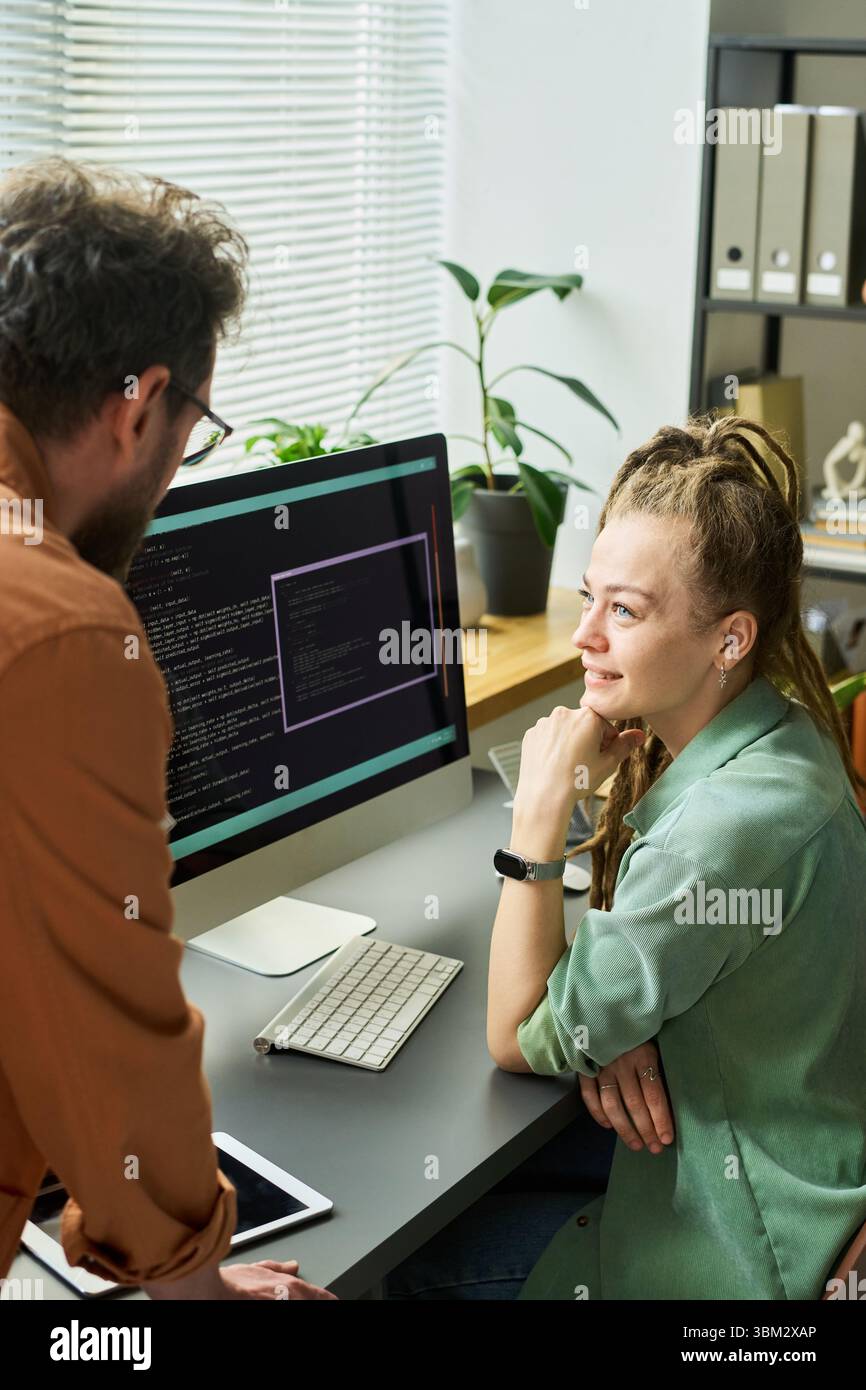 Young Caucasian Woman Collaborating with Colleague on Neural Network Coding Stock Photo