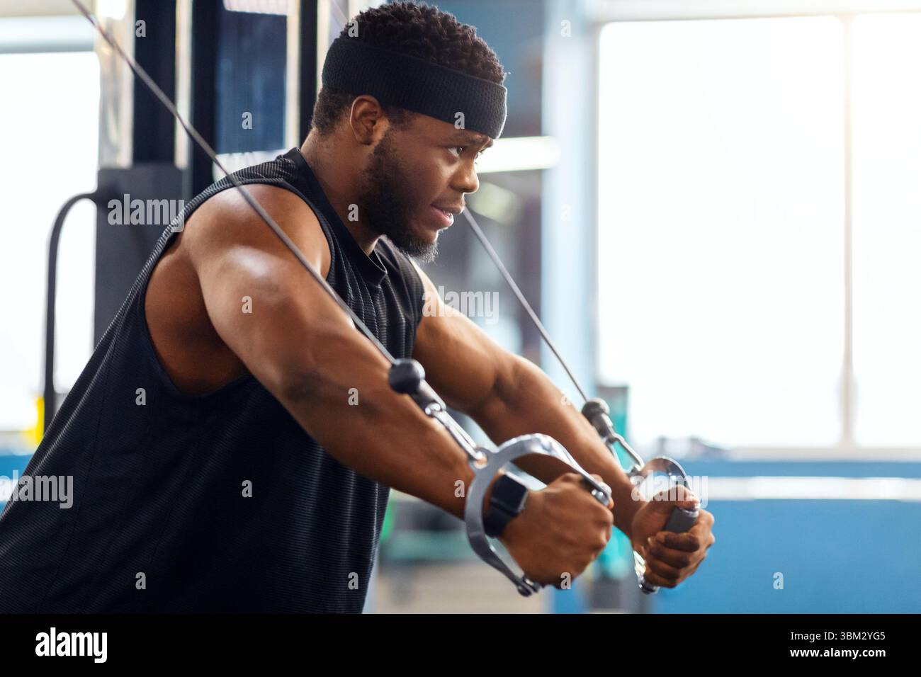 Young black sportsman training triceps on block exerciser in gym Stock Photo