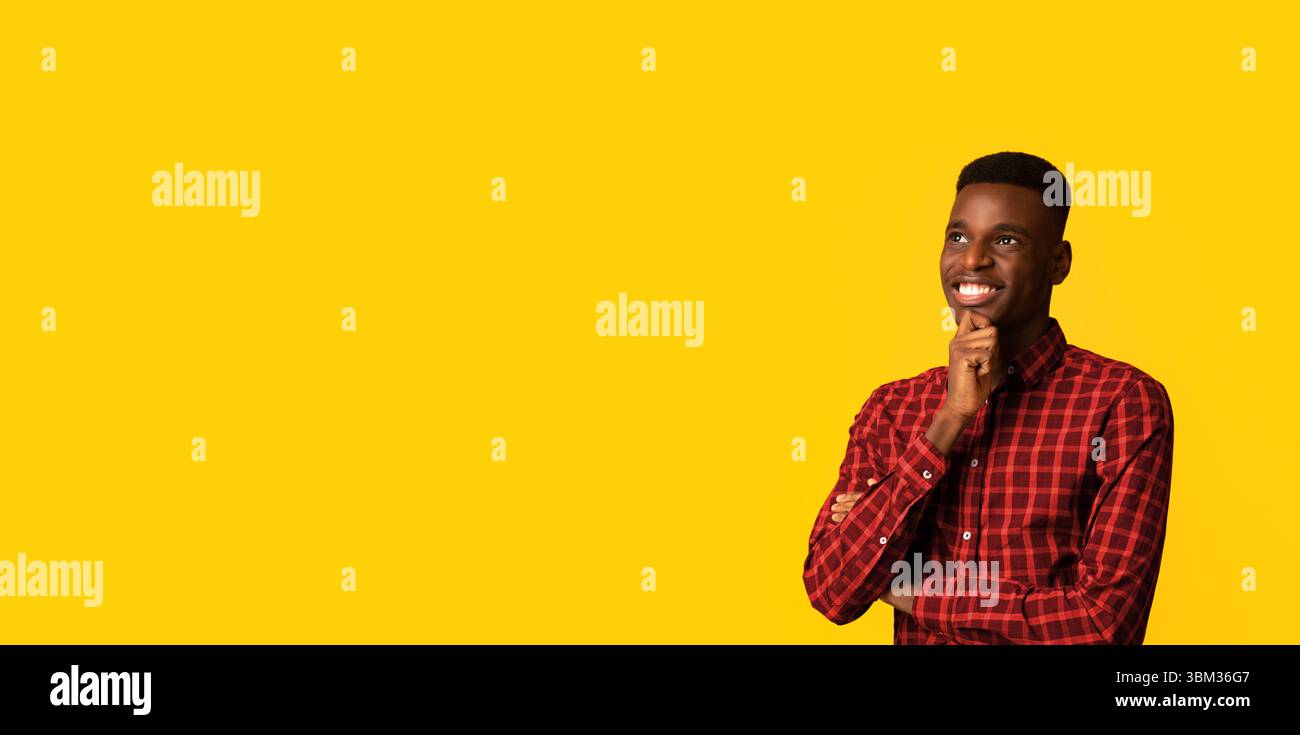 Portraif Of Pensive Dreamy African American Guy Standing Isolated On Yellow Background Stock Photo