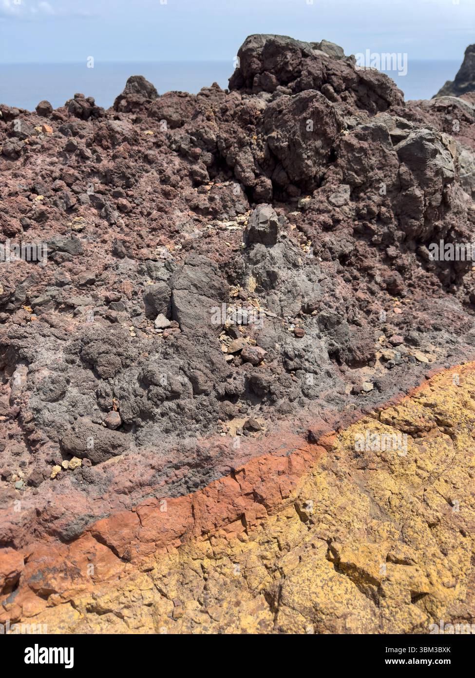 Layered texture of volcanic rocks, background with warm orange, yellow and gray stripes. Layers indicate ancient geological processes, creating a natu - Smartphone Captured Stock Image