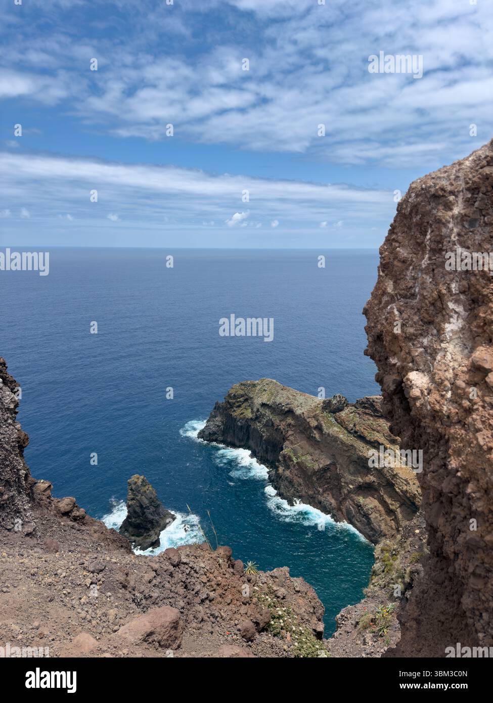 Photo of small bay on Madeira island, high rocky coastline, ocean waves crashing on large rocks, mountains. Travel concept - Smartphone Captured Stock Image