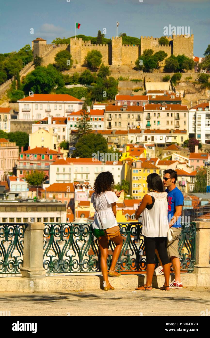 Tourists enjoy panoramic views of Castelo de São Jorge from São Pedro de Alcântara viewpoint's ornate balustrade, Lisbon, Portugal Stock Photo