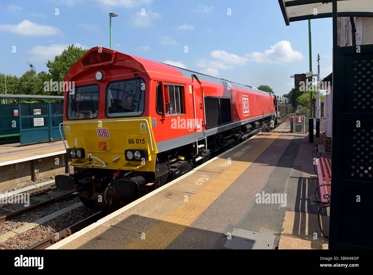 DB Cargo diesel loco 66015 with a train of new cars passing  Ridgmont Railway Station, Bedfordshire, 11th June 2025 Stock Photo