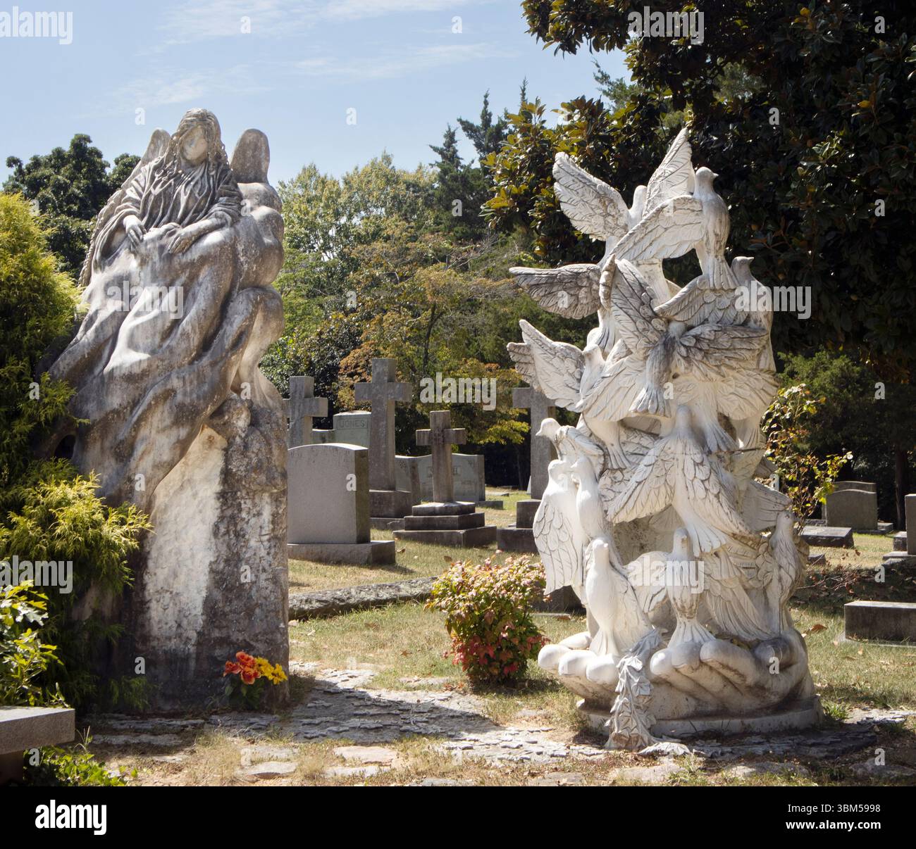 Peaceful cemetery scene with angel and dove statues bathed in sunlight at Oakwood Cemetery in Raleigh, North Carolina. Stock Photo