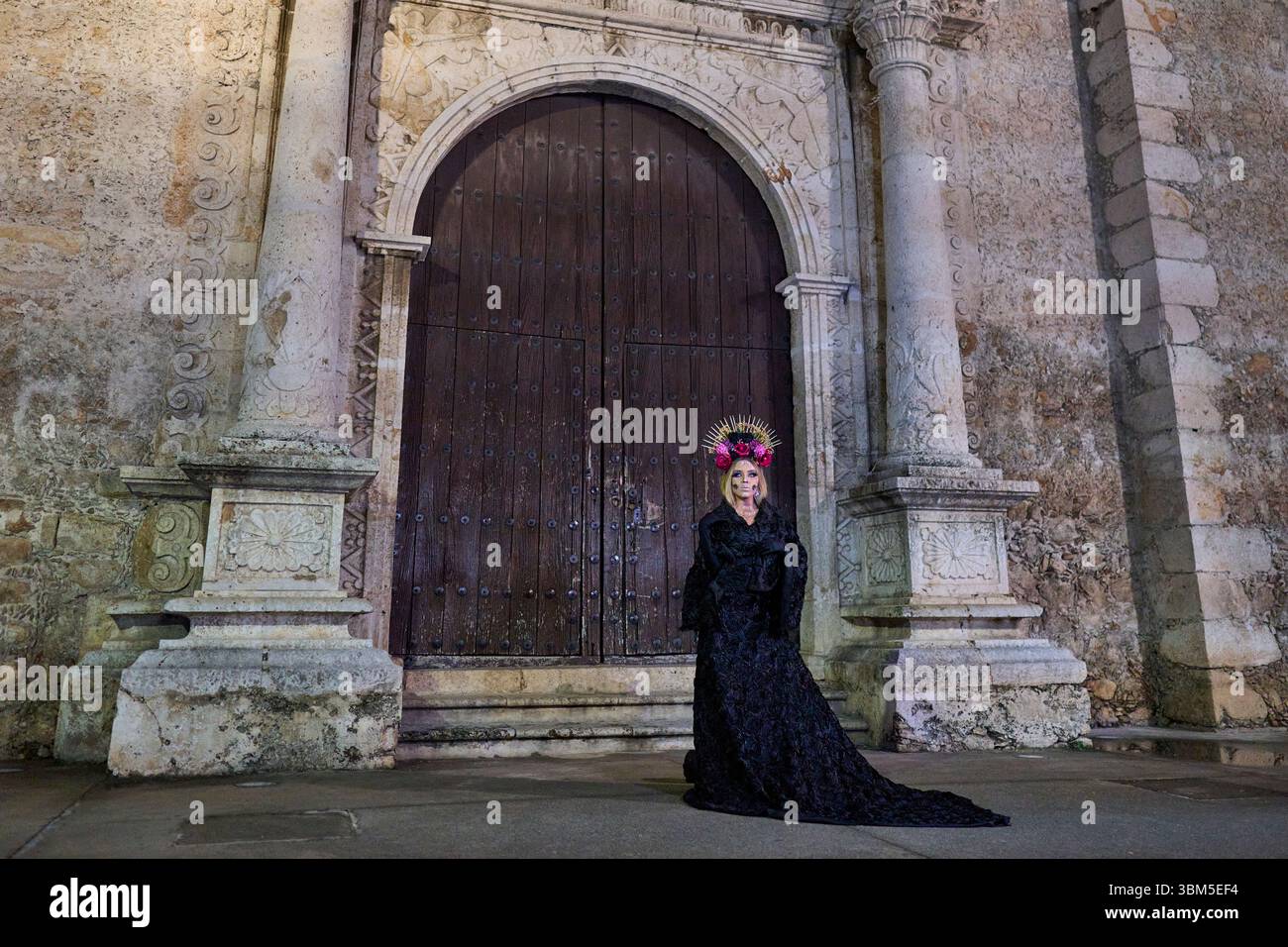 Mexico, Merida. Woman in Catrina costume and makeup poses before ancient church doors, celebrating Day of the Dead. (Editorial Use Only) Stock Photo