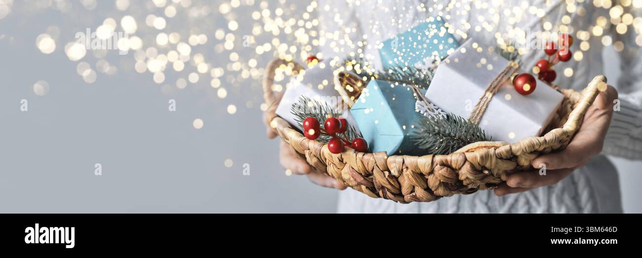 Frau halten Korb mit nachhaltig verpackt Weihnachtsgeschenke, Nahaufnahme, selektive Fokus. Eco Weihnachtsdekor, Banner-Format Stock Photo