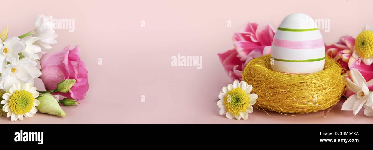 Easter creative composition. Spring flowers, Easter egg and butterflies on pink banner. Easter card Stock Photo